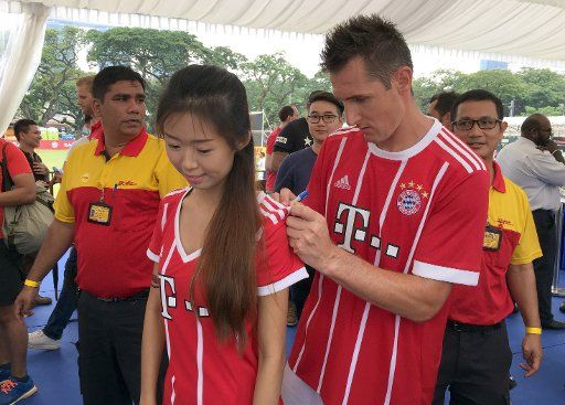 Former professional soccer player Miroslav Klose an autograph to a female fan during the FC Bayern Munich Media Day in Singapore, 26 July 2017. Photo: Klaus Bergmann\/