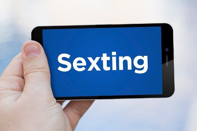 man holding a smartphone with sexting app . Screen graphics are made up.