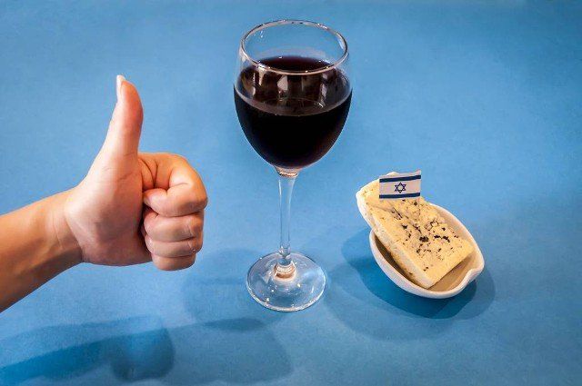 Hand of a young woman showing like to Israeli cheese and Israeli wine. Anti-BDS campaign. Resisting Antisemitism concept, supporting Israeli products.