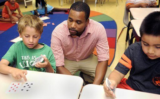 David Wise, center, works with Zachary Fiorenza, left, and Raul Saldana-Hernandez in their second grade summer school math class July 25, 2014 in Baltimore, Md. Wise is part of the Urban Teacher Program, and is a new teacher who spent a year as a...