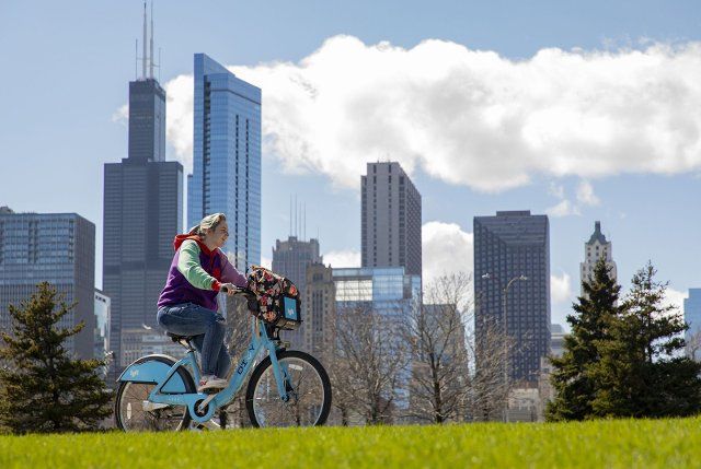 A Divvy bike rider rides the lakefront trail in front of the Chicago skyline on a sunny spring day, April 14, 2022. (Brian Cassella\/Chicago Tribune\/TNS