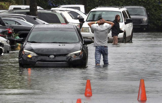 A driver climbs out of his stalled car after he tried to move it to higher ground in the parking lot at the Beachwallk at Sheridan Apartments in Dania Beach, Florida, on Saturday, June 4, 2022, as rains from the storm forecast to become Tropical Storm Alex cause flooding throughout South Florida. (Mike Stocker\/South Florida Sun Sentinel\/TNS