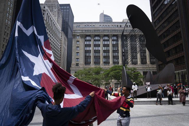 Tendaji Andrews-Hutchinson, right, helps unfurl the Chicago Juneteenth flag during a ceremony at Richard J Daley Center Plaza on June 13, 2022. (E. Jason Wambsgans\/Chicago Tribune\/TNS