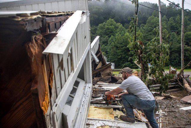 Sammy Gibson uses a chainsaw to cut apart a house that came to rest on a bridge near the Whitesburg Recycling Center in Letcher County, Kentucky, on Friday, July 29, 2022. (Ryan C. Hermens\/Lexington Herald-Leader\/TNS