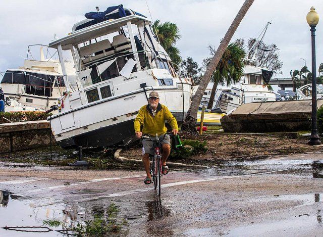 A biker rides byf boats that were run aground in the Legacy Harbour Marina in Fort Myers a day after Hurricane Ian hits the West Coast of Florida as Category 4 storm, on Thursday, Sept. 29, 2022. (Pedro Portal\/Miami Herald\/TNS