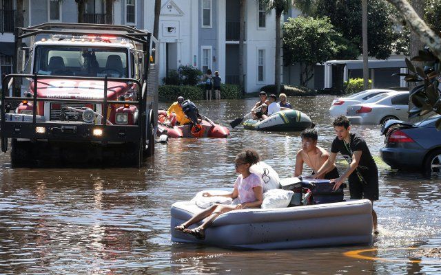 With Orange County Fire Rescue on the scene, residents of Arden Villas apartments use rubber boats, air mattresses and kiddie pools to float their belongings out of their homes, Sept. 30, 2022, after heavy rains from Hurricane Ian flooded the complex near the University of Central Florida. (Joe Burbank\/Orlando Sentinal\/TNS