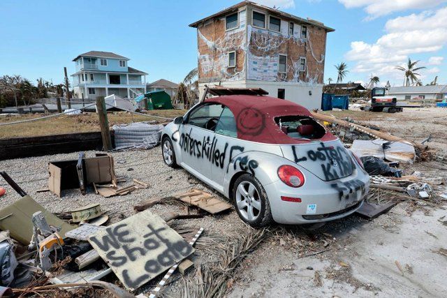 Makeshift signs are displayed in front of a damaged home, caused by Hurricane Ian in St. James City, an unincorporated Florida community, on Pine Island on Tuesday, Oct. 4, 2022. (Al Diaz\/Miami Herald\/TNS