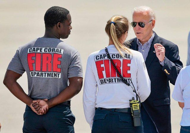 President Joe Biden, right, and first lady Jill Biden, not pictured, touched down on the runway of Southwest Florida International Airport in Fort Myers, Florida. They were greeted by a line of local officials, Cape Coral firefighters and members of FEMA before boarding the Marine One helicopter as he made his way to hard-hit areas of Fort Myers still recovering from Hurricane Ian on Oct. 5, 2022. (Al Diaz\/Miami Herald\/TNS
