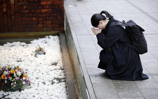 A woman prays at an amusement park in Kobe, Japan, on Jan. 17, 2018, the 23rd anniversary of the Great Hanshin Earthquake that killed more than 6,000 people. (Kyodo) ==Kyodo