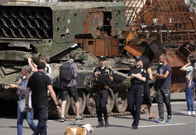 People look at a Russian tank destroyed in the country\
