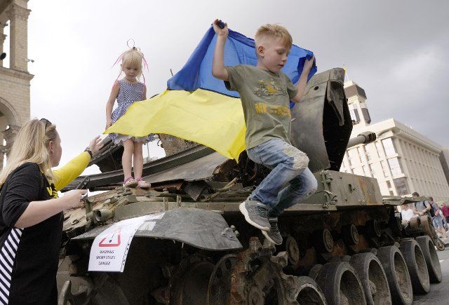 Children play on a Russian tank destroyed in the country\