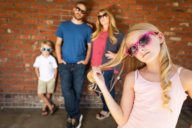 Cute young caucasian girl wearing sunglasses with family