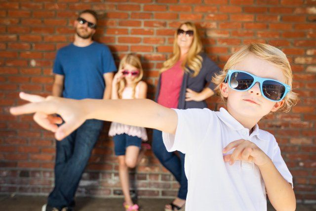 Cute young caucasian boy wearing sunglasses with family