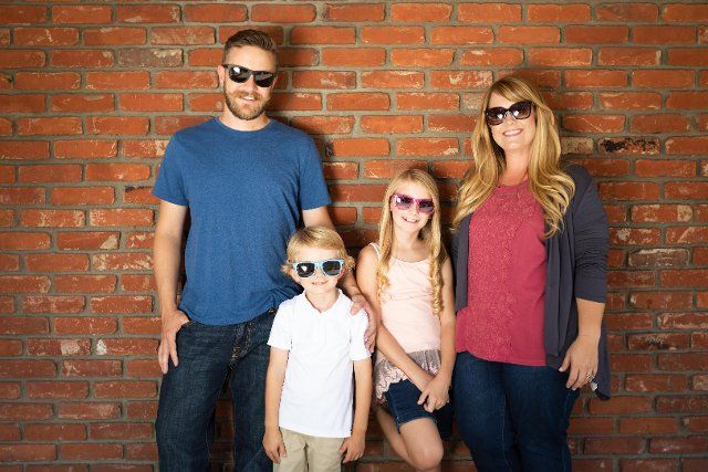 Young caucasian family wearing sunglasses against brick