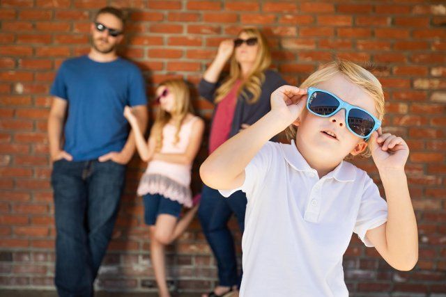 Cute young caucasian boy wearing sunglasses with family