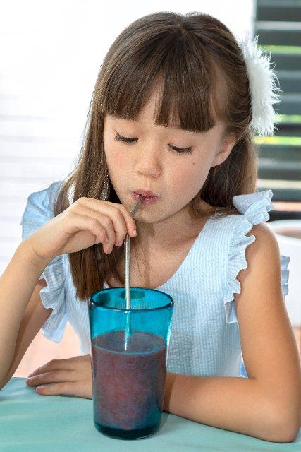 Eight year old girl drinking from a metal