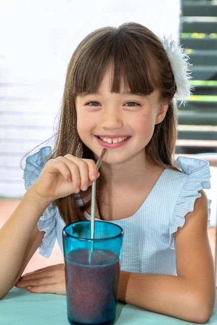 Eight year old girl drinking a smoothie from a metal
