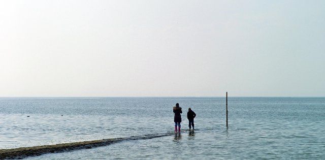 Two people on a groyne on the North Sea coast in Cuxhaven Sahlenburg, Cuxhaven district, Germany