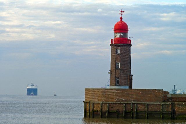 Bremerhaven, lighthouse at the mouth of the river Geese, in the background a car transporter with two tugs, Germany