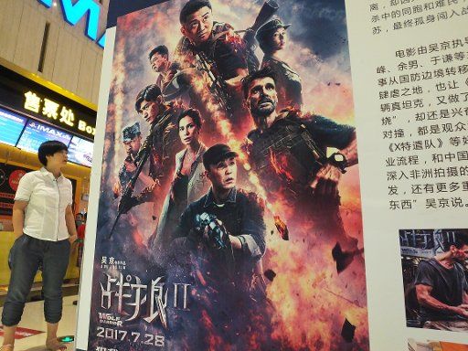 --FILE--A Chinese filmgoer walks past a poster of the Chinese action movie "Wolf Warriors 2" directed by Wu Jing at a cinema in Yichang city, central China\