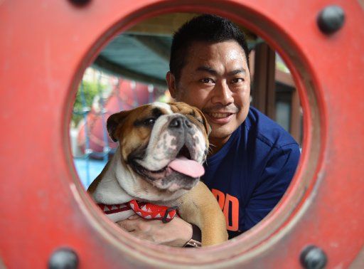 Tim Leung and his bulldog Oxford, who placed first in a competition to see which do looks most like its owner, poses after the presentation and appearance of dog whisperer Cesar Millan (unseen) at the National Geographic Channel Rescue day at ...