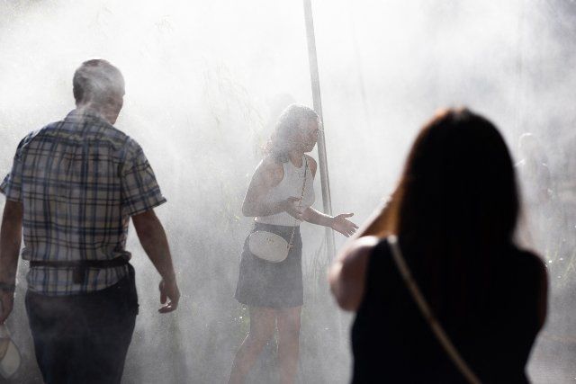 People enjoy a water fogger on the Quai de Seine during a heat wave in Paris on July 13, 2022. After Spain and Portugal, France is witnessing a second heatwave in less than a month, a sign of climate change and hotter summers to come where 35 degrees will be the norm said the French weather broadcast company Meteo France. Photo by Raphael Lafargue\/Abaca\/Sipa
