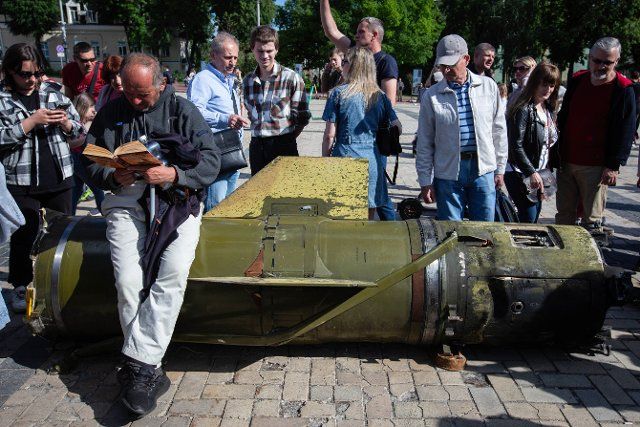 A man reads a book while sitting on a Russian Tochka U missile defused by sappers and displayed at an exhibition of Russian military hardware destroyed during Russia\