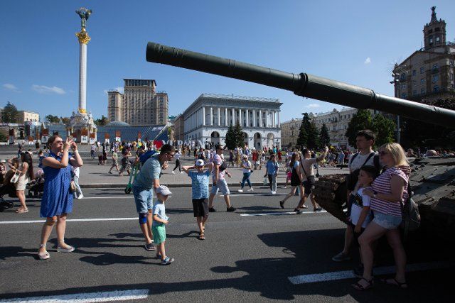 People take photos in front of a destroyed Russian tank displayed on the main street Khreshchatyk as part of the upcoming celebration of the Independence Day of Ukraine amid Russia\
