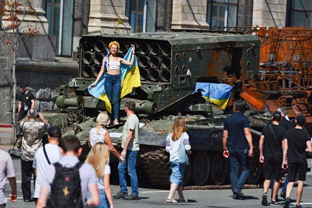 A girl holding a Ukrainian flag poses on the jet system Solntsepek as people inspect the destroyed Russian army equipment displayed at Khreshchatyk in the center of Kyiv. Captured Russian military equipment is being temporarily displayed on Khreschaytk street in the heart of the Ukrainian capital. The area has become a popular attraction among residents curious to see Ukraine\