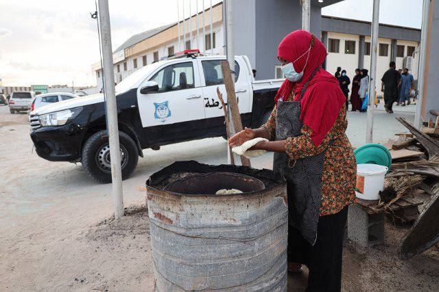 A woman from the city of Ubari in the south of the country turns the bread in her hands in the traditional oven to sell it on the occasion of the Prophet\