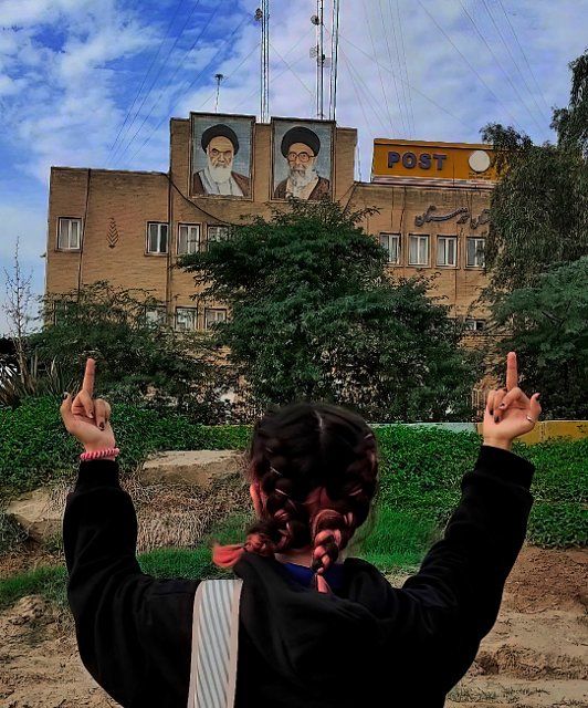 Iranian woman without the headscarf mandatory for women giving the middle finger to the pictures of Ayatollah Khomeini, the founder of the Islamic Republic and Ayatollah Ali Khamenei, the leader of the Islamic Republic of Iran on the wall of post office in Khuzestan region in south of Iran, unrest continue in Iran since the murder of Mahsa Amini, Iranians have been holding daily protests anti-regime continue with intensity. Khuzestan. Iran. November 18, 2022. Photo by SalamPix\/Abaca\/Sipa