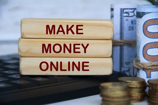 Make money online text on wooden blocks on top of keyboard computer with gold coins and bank notes. Online business concept