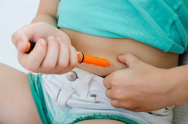 Child injects himself with insulin in the abdomen at home. Medicine,  Diabetes,  Glycemia and Health care concept