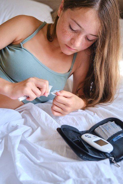 A teenage girl takes a test strip to measure blood sugar using a glucometer. Lifestyle of a child with diabetes.