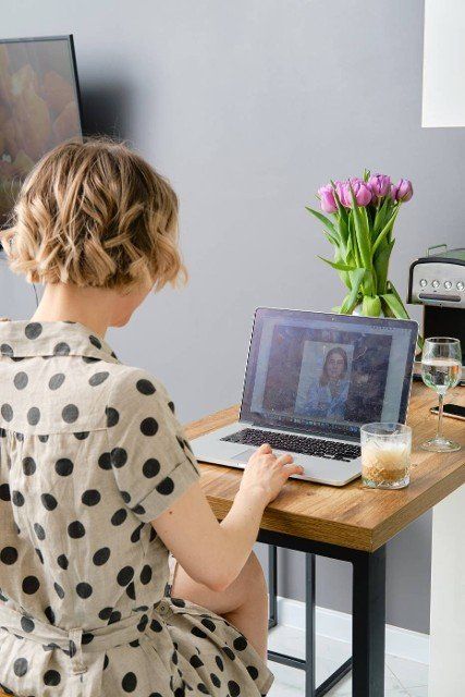 Back view of a woman making video call to business partner using laptop,  looking at screen with virtual web chat