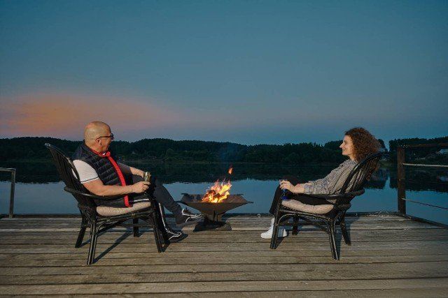 Couple sits on the pier next to the fireplace and watches the sunset