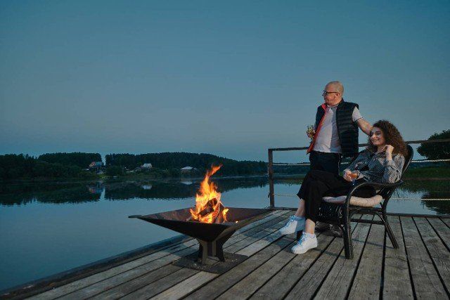 Couple is relaxing in the evening silence on the pier near the fire