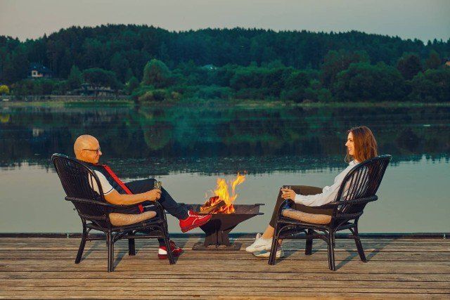 Couple rests in the evening sitting on the pier by the fire