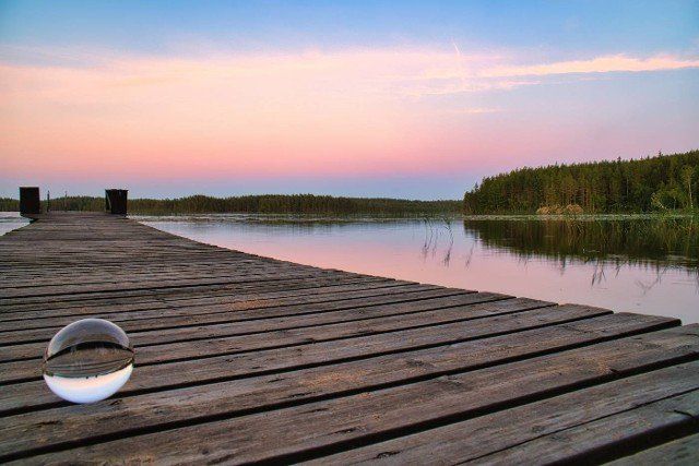 Glass ball on a wooden pier at a Swedish lake at evening hour. Nature shot from Scandinavia