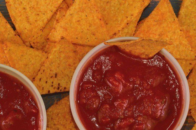 Chili corn-chips with salsa dip on wooden background.