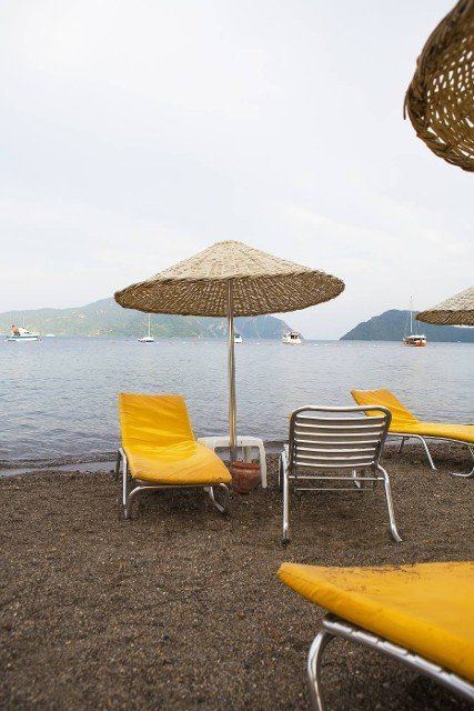 Beautiful yellow chaise lounges and umbrellas made from straw on the beach of Marmaris
