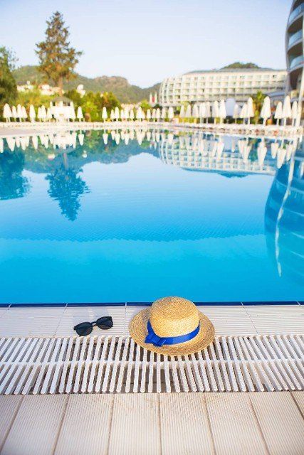 The concept of summer vacation - glasses,  straw hat on the background of the hotel complex.