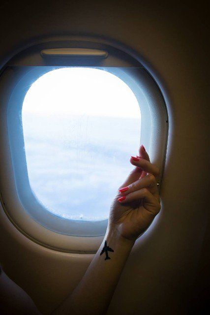 beautiful view from the airplane window on the air clouds,  hand of a girl with a tattoo