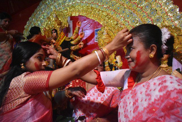 Hindu women apply "sindhur", or vermillion powder, on each other\