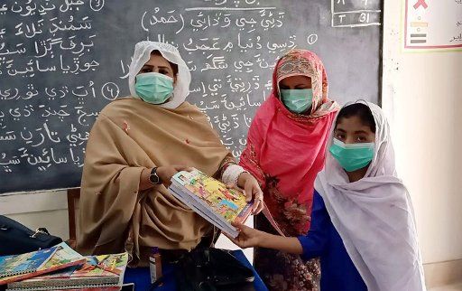 MADEJI, PAKISTAN, OCT 05: District Education Officer, Zakia Pathan is distributing books among the girl students with SOPs levels on government guidelines of face mask and social distancing as preventive measure against the spread of the Coronavirus (COVID-19), after reopened school almost six months closure due to Covid-19 pandemic, at the Government Girls Primary School-2 in Madeji on Monday, October 05, 2020. (Jamal Dawoodpoto\/PPI Images