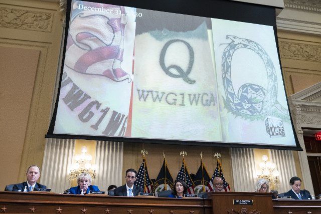UNITED STATES - JULY 12: QAnon imagery appears on a screen during the Select Committee to Investigate the January 6th Attack on the United States Capitol hearing to present previously unseen material and hear witness testimony in Cannon Building, on Tuesday, July 12, 2022. Appearing from left are, Rep. Adam Schiff, D-Calif., Rep. Zoe Lofgren, D-Calif., counsel, Rep. Stephanie Murphy, D-Fla., Chairman Bennie Thompson, D-Miss., vice chair Rep. Liz Cheney, R-Wyo., and Rep. Jamie Raskin, D-Md. (Tom Williams\/CQ Roll Call