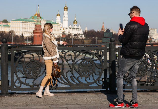 MOSCOW, RUSSIA â MARCH 19, 2022: People take pictures on Patriarshy Bridge with the State Kremlin Palace, the Ivan the Great Bell Tower, and the Cathedral of the Archangel in the background. Mikhail Metzel\/TAS