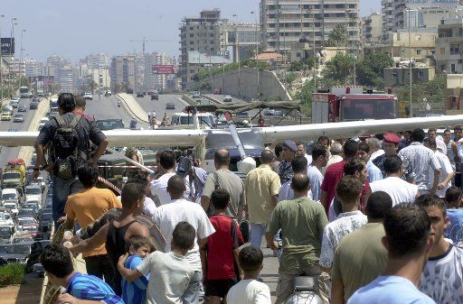 People gather to look at a small plane that landed on a busy highway in Beirut on July 3 2004 after experiencing technical problems. According to witnesses the pilot had the presence of mind to stick his head out of the window and yell at the...