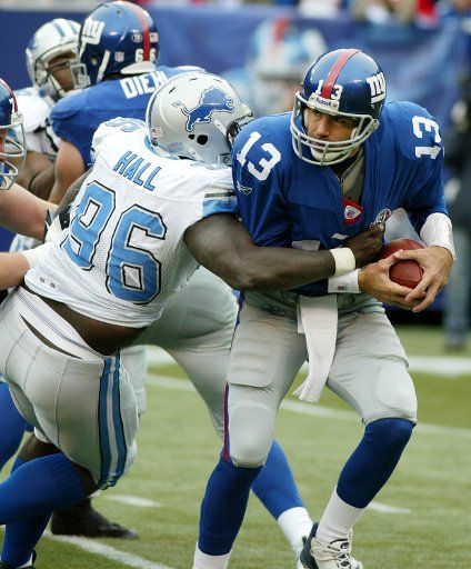 New York Giants quarterback Kurt Warner tries to escape the grasp of Detroit Lions defender James Hall.  The Detroit Lions defeated the New York Giants 28 to 13 at Giants Stadium in East Rutherford New Jersey on October 24 2004.    (UPI Photo\/John...