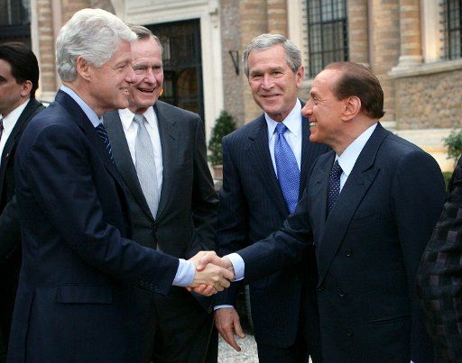 President George W. Bush and his father former President George Bush look on as Italian Prime Minister Silvio Berlusconi and former President Bill Clinton shake hands Thursday April 7 2005 prior to dinner at the Prime Minister\
